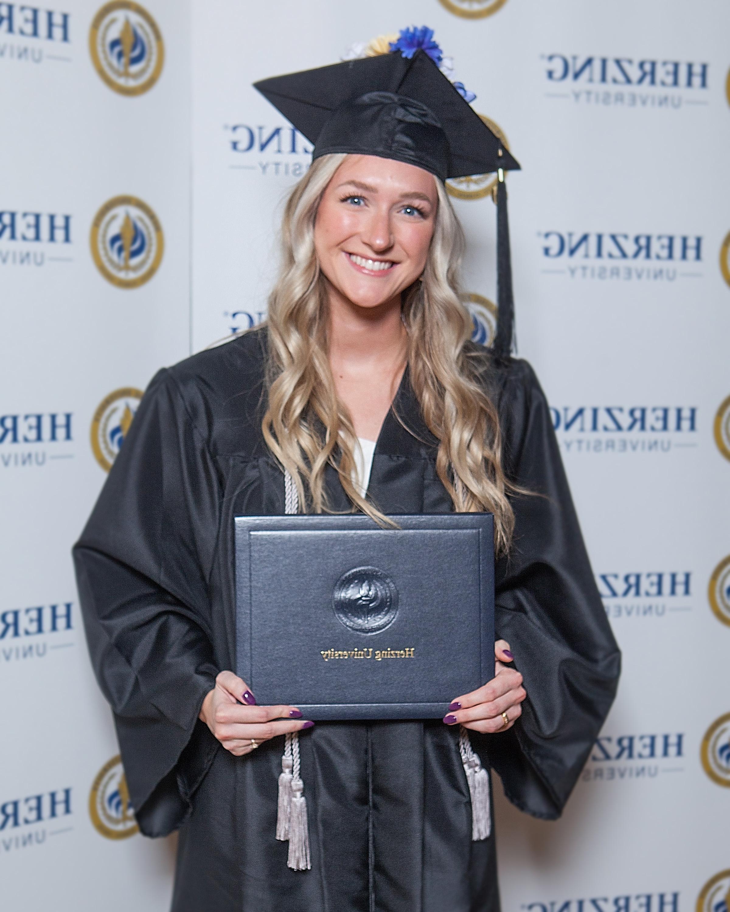 Herzing graduate smiling 和 holding degree